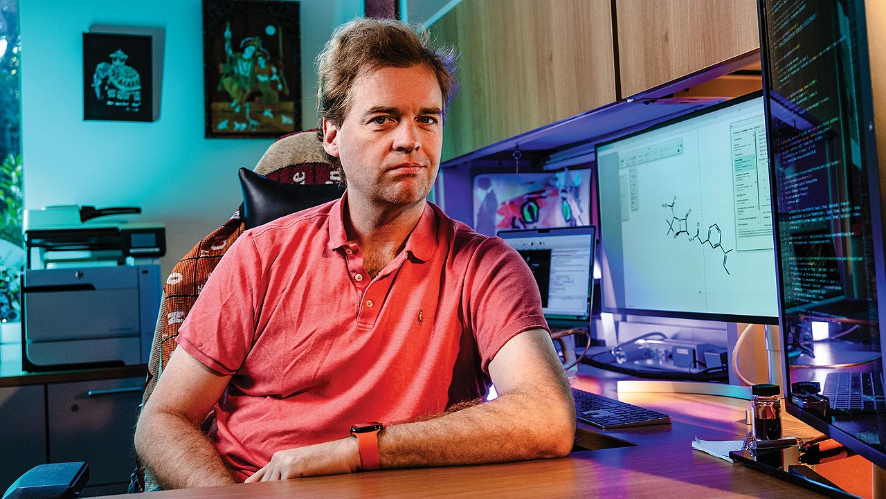 A person sits at a computer with molecule drawings on the screen.