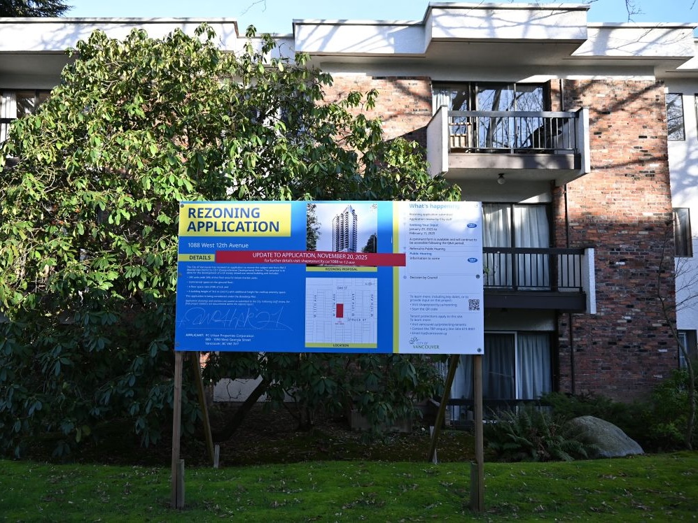 A redevelopment sign in front of a brick apartment building.