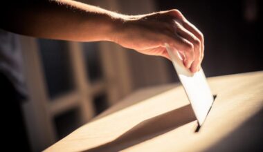 A person places a ballot into a box in a dimly lit room.