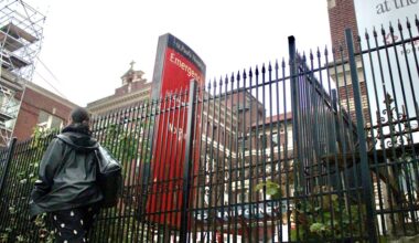 The fence outside St. Paul&rsquo;s Hospital. A person walks by.