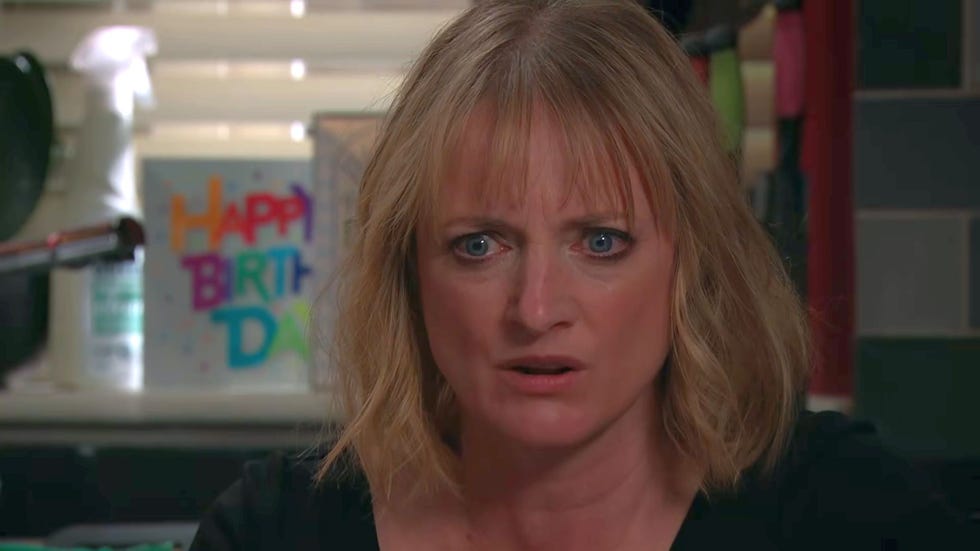 emmerdale nicola king close up, sat at the table with a shocked looked on her face, and a birthday card in the background