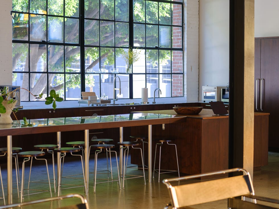 Bright kitchen with large windows, wooden countertops, modern appliances, and metal stools.