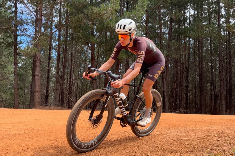 A woman in lycra and sunglasses cycling.