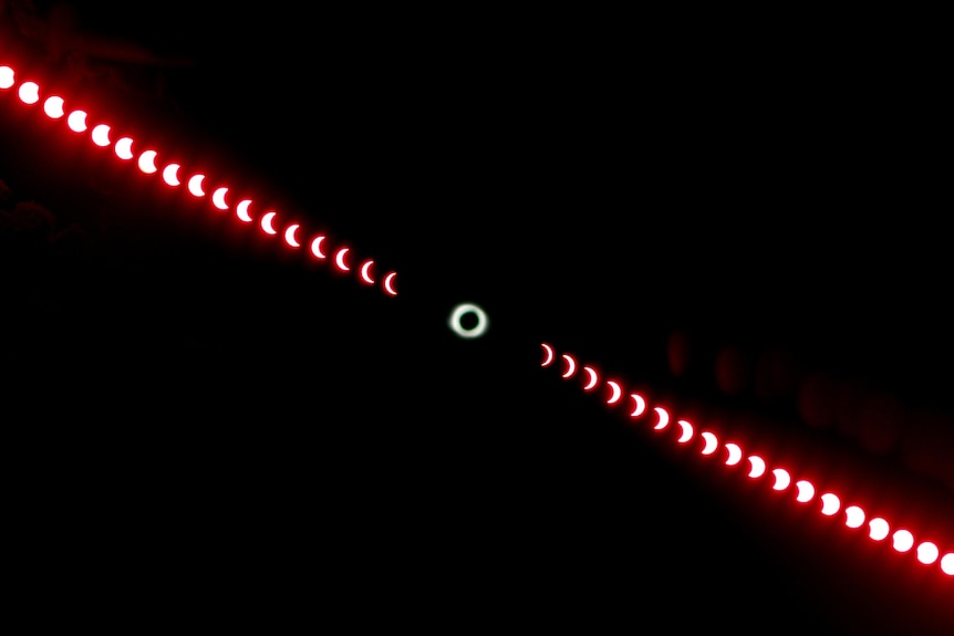 Time lapse photo of red Sun slowly being covered and then uncovered by the Moon against a black background.