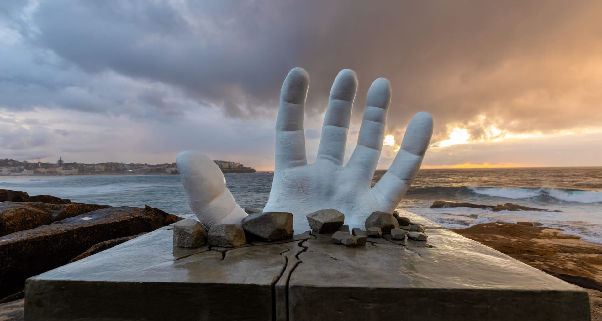 a sculpture of a giant hand breaking through the ground at Bondi Beach, NSW, Australia