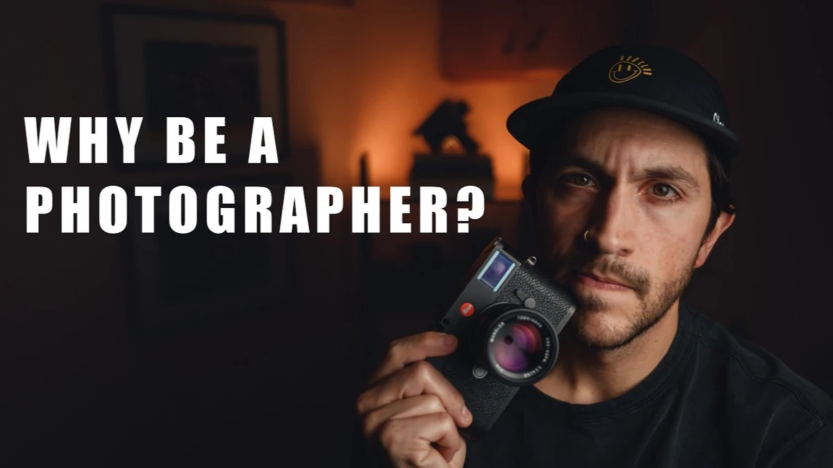 Man in a black cap holding a black rangefinder camera, with the title 'Why Be a Photographer?' overlaid on the left