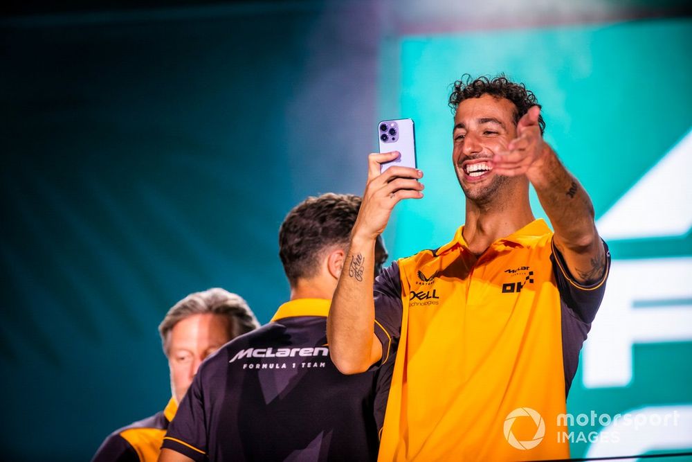 Daniel Ricciardo, McLaren, takes a photo on stage at the Miami Opening Party, in front of Zak Brown, CEO, McLaren Racing, Lando Norris, McLaren 