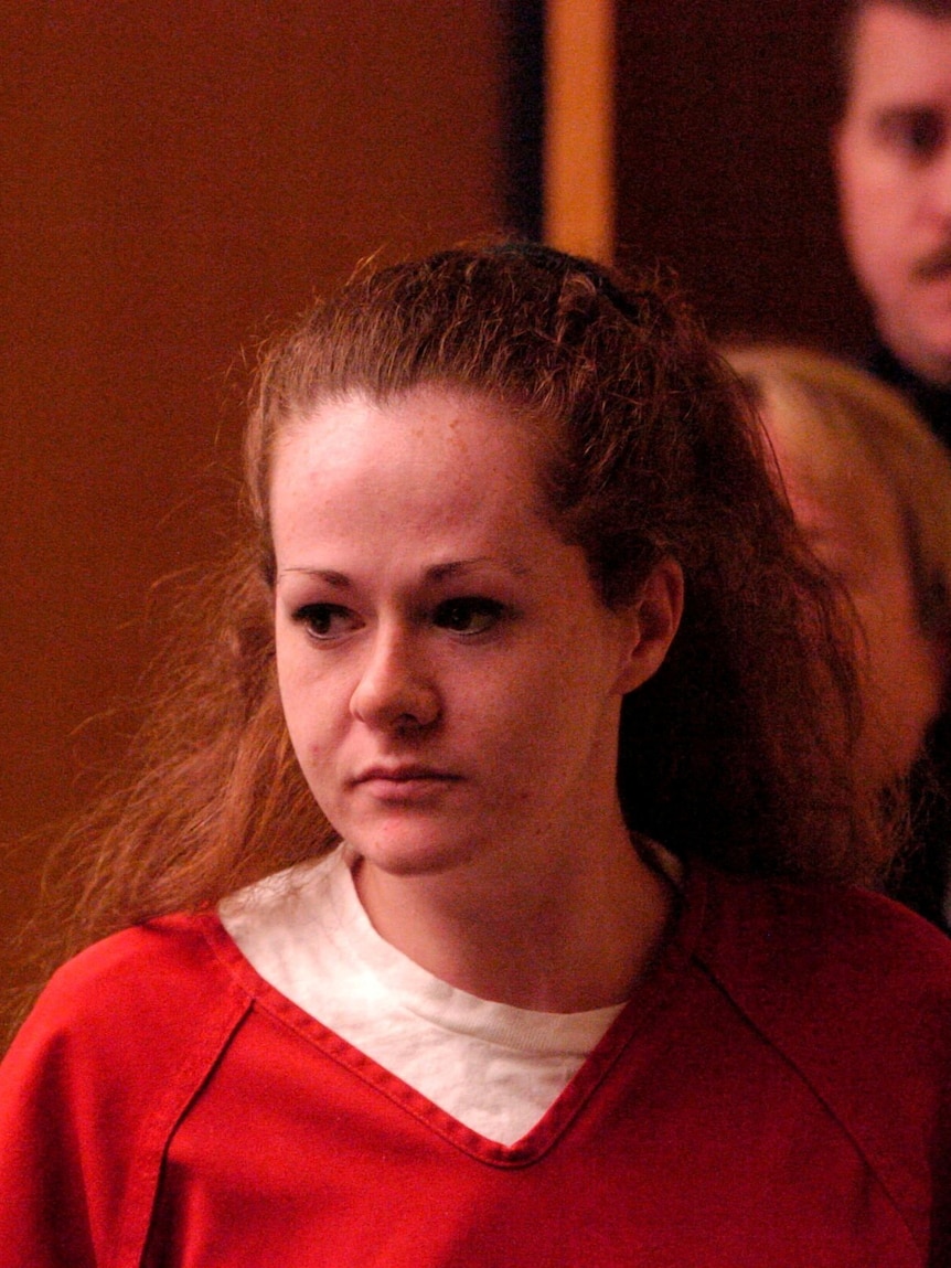 a young woman in a prison uniform enters a courtroom