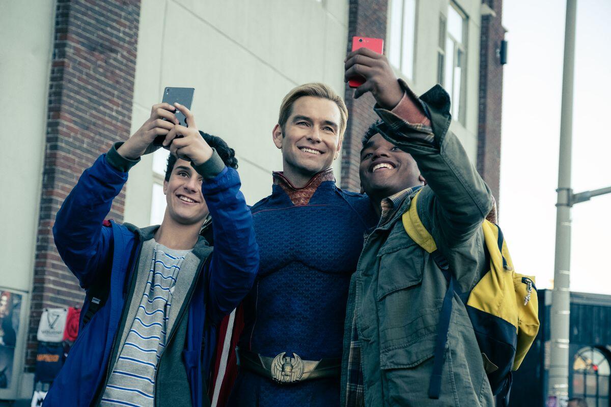 Antony Starr as Homelander poses for selfies with two younger male fans.