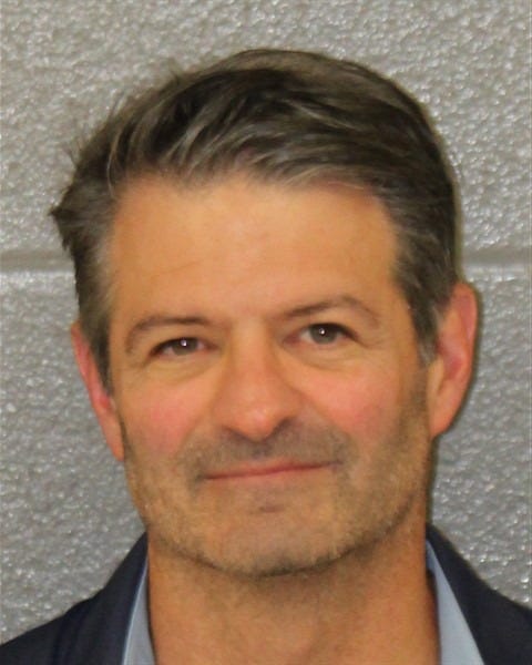Man with short gray hair and a slight smile against a gray background.