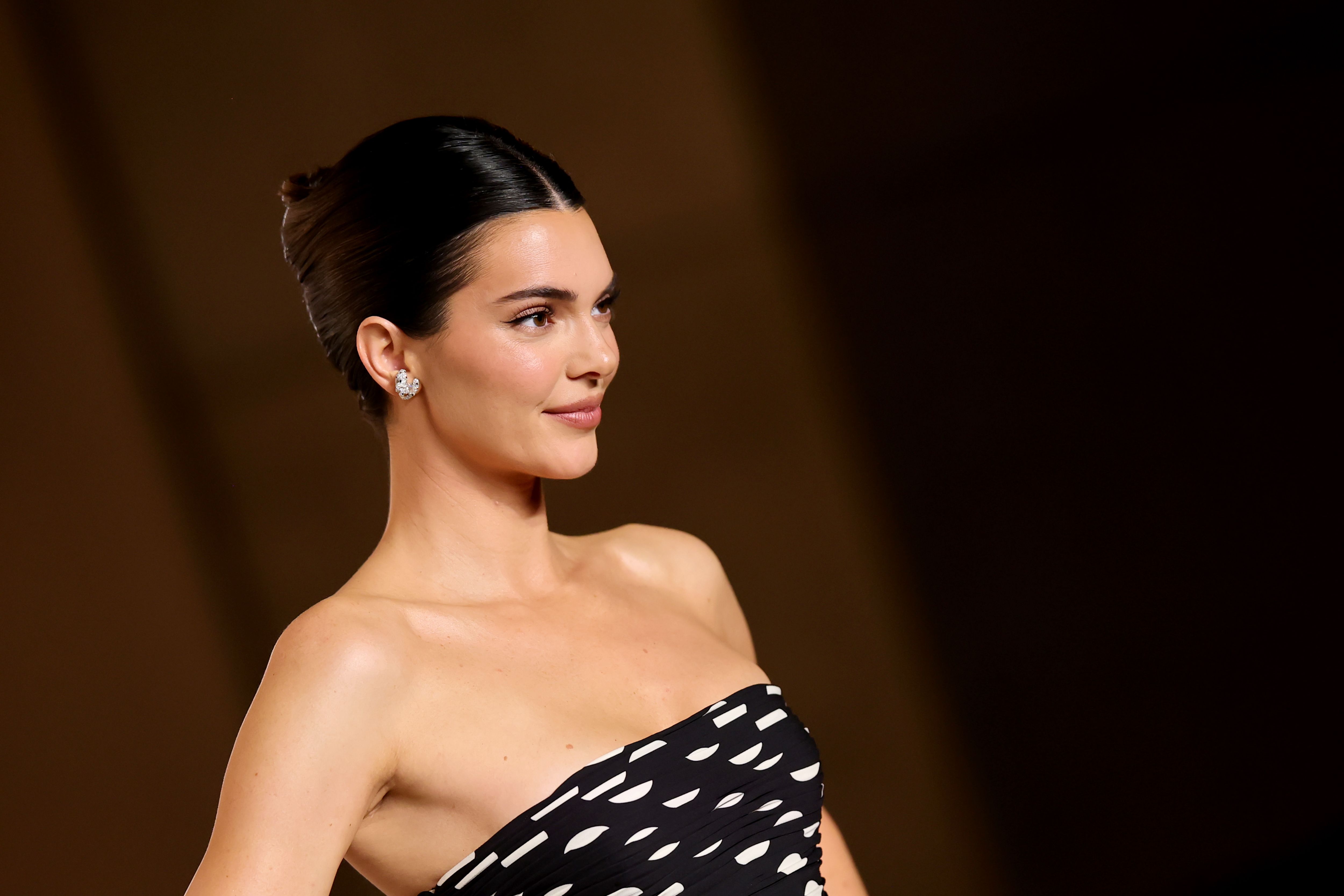 Kendall Jenner attends the Academy Museum Gala wearing a black-and-white patterned strapless dress and her hair styled in an updo.