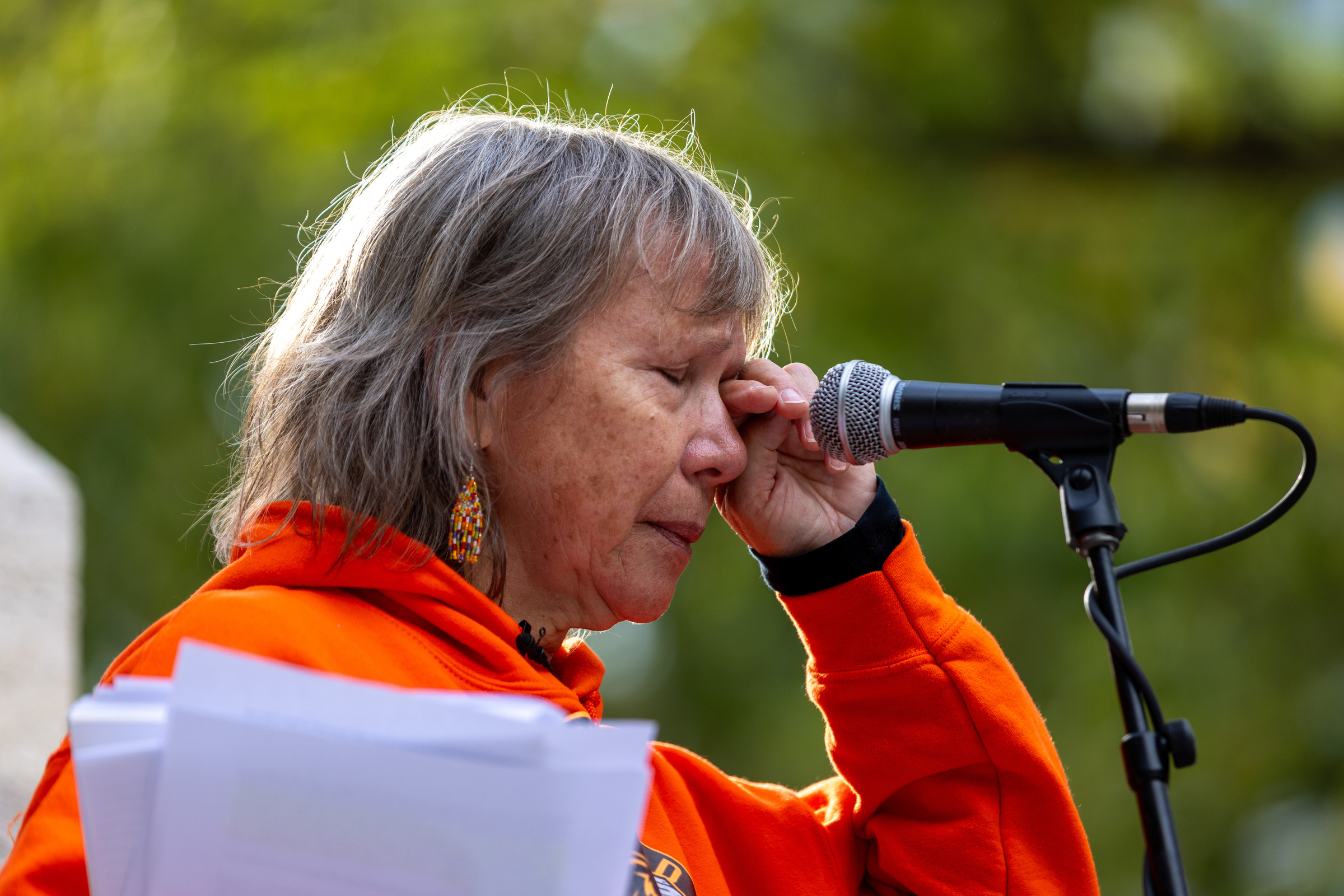 Ellen Gabriel wipes a tear from her eye as she speaks at a microphone outside.