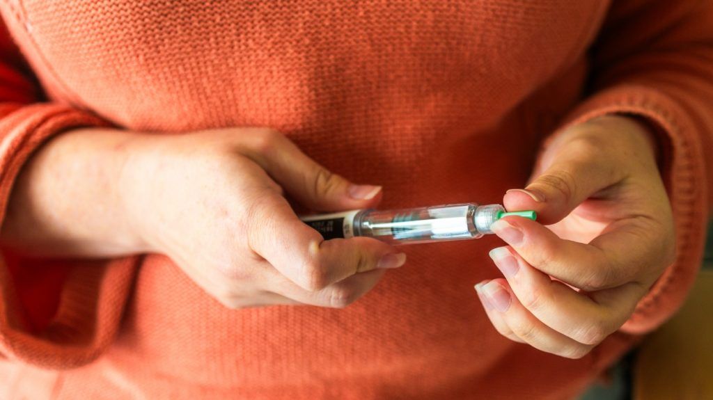 A person prepares to inject themselves with a GLP-1 medication for weight loss and diabetes management