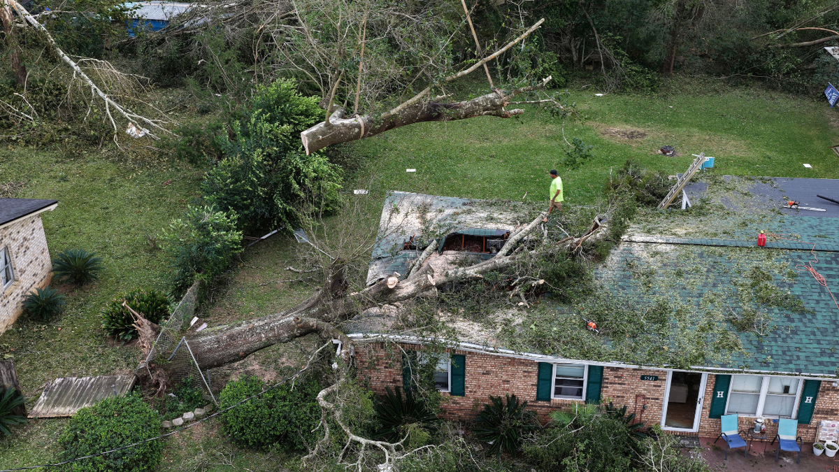 In an aerial view, a worker with Southern Land Services removes a tree that landed on a home when Hurricane Isaias passed through the area on October 10, 2026, in Milton, Florida.