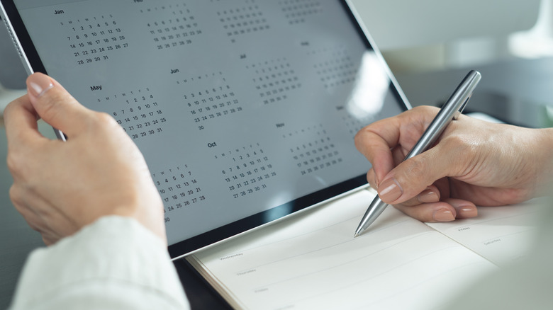 A person using a tablet and paper notepad