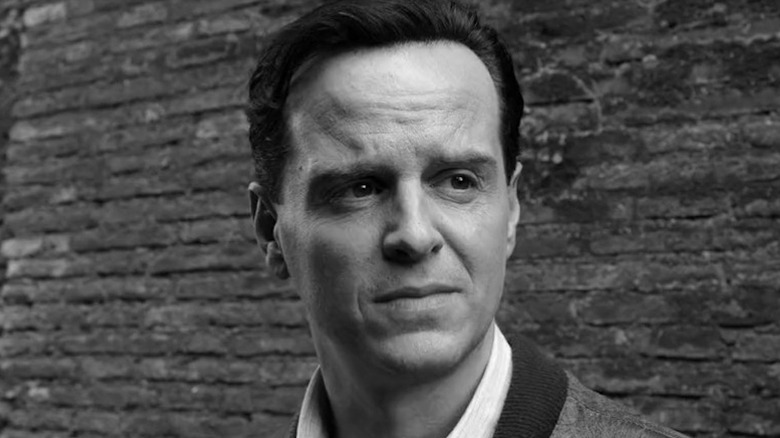 Andrew Scott as Ripley in black and white standing in front of brick wall in Ripley
