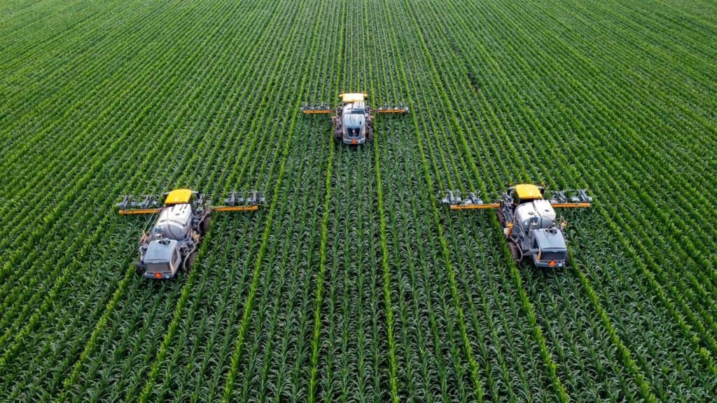 Large agricultural field with three farming machines at work