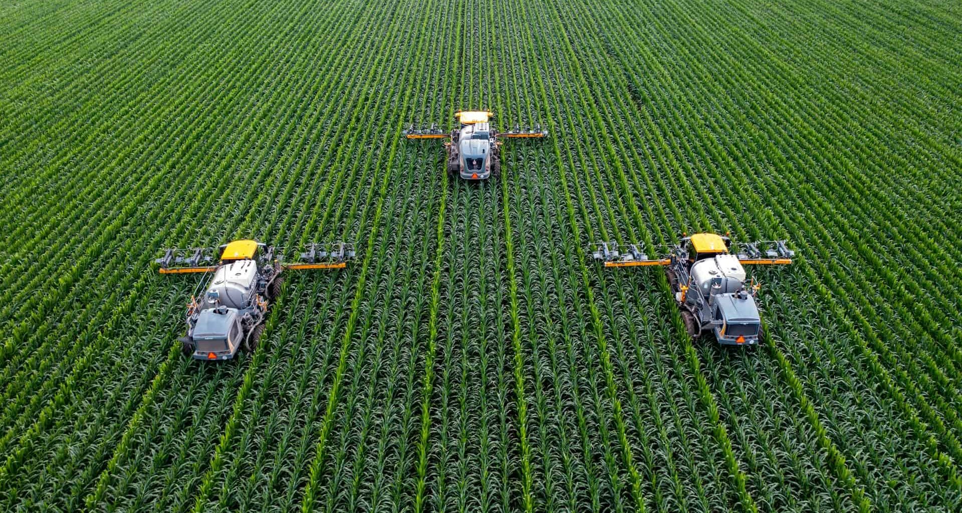 Large agricultural field with three farming machines at work