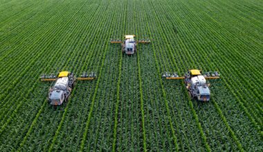 Large agricultural field with three farming machines at work
