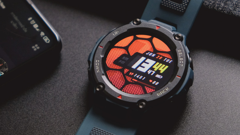 An Amazfit T-Rex Pro displaying the time against a colorful patterned background