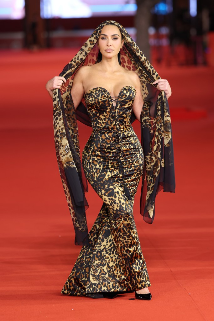 Kim Kardashian on the red carpet wearing a leopard print gown and matching hooded scarf.
