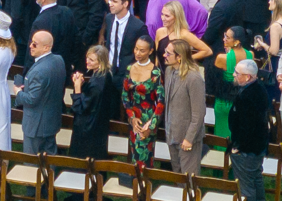 Attendees at the wedding, including Zoe Saldaña and other guests standing by rows of chairs.