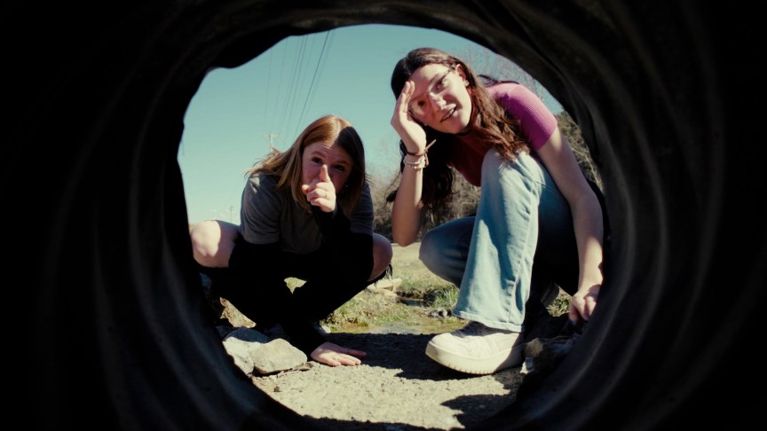 Two teenage girls look in a pipe in a production still from Murder 101.