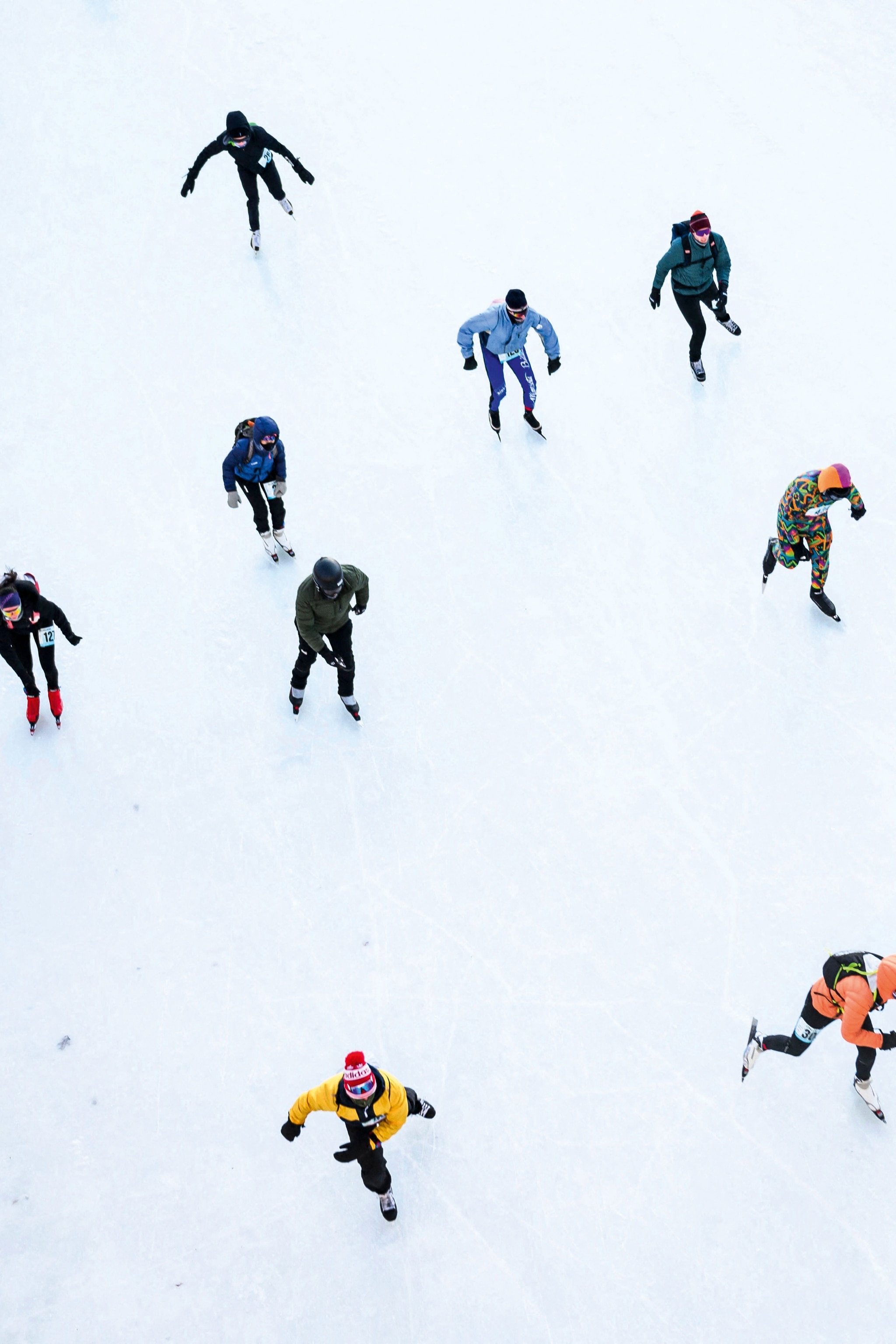 Aerial view of ice skaters on white ice