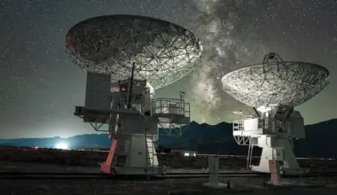 Two large radio telescope dishes pointing skyward beneath the Milky Way at night