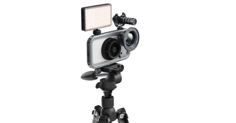 A smartphone mounted in a protective cage on a tripod, equipped with an external LED light, a microphone, and a lens attachment.