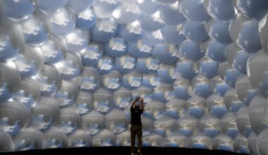 the interior of an architectural, inflatable compound camera installation with a person standing inside it, looking up at bubble-like forms featuring images of outside captured by tiny apertures