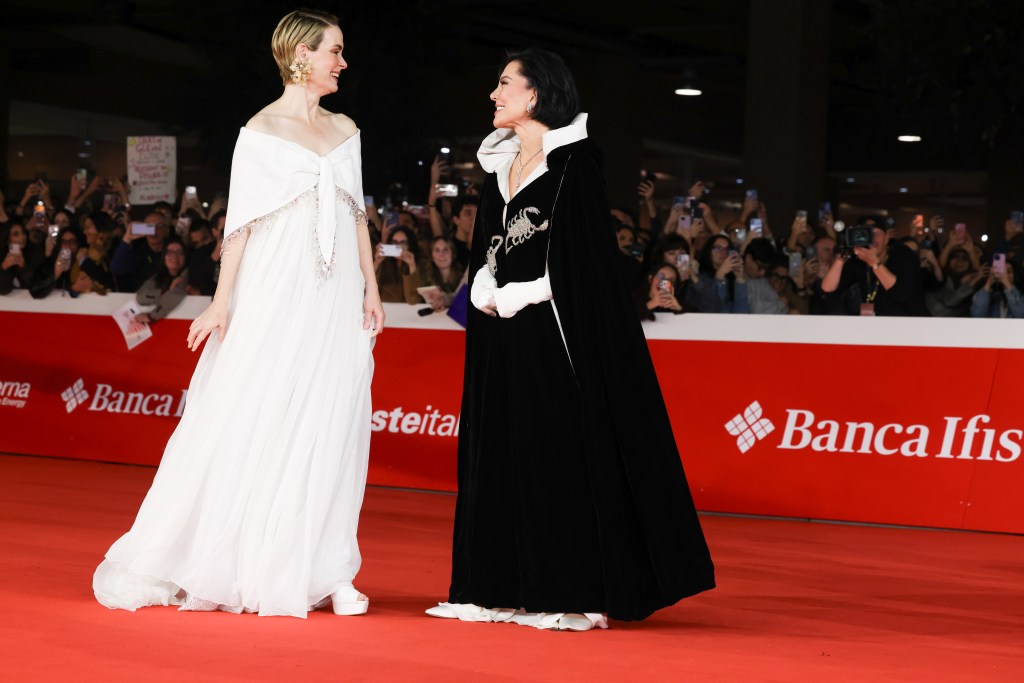 Sarah Paulson and Kris Jenner stand on a red carpet, smiling and looking at each other.