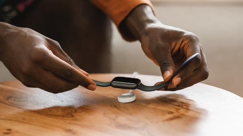 A person putting Apple Watch on its charger