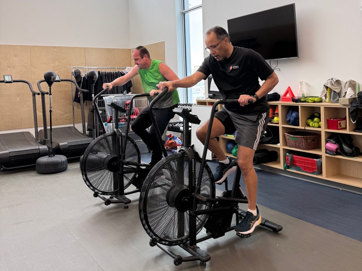 two men riding stationary exercise bikes in a gym