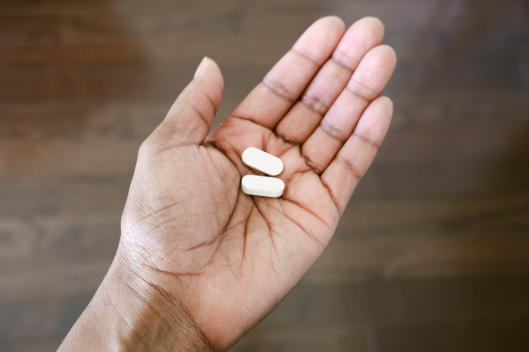 Close-up of a hand holding two white pills.