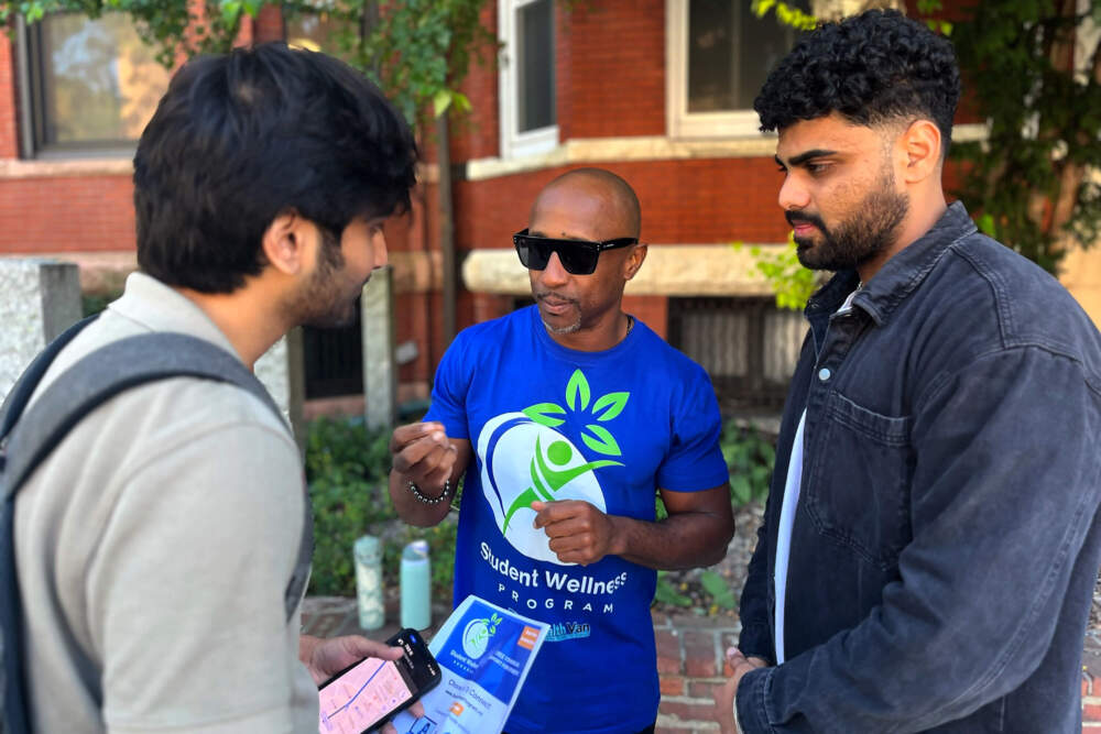 Dion Rambo tells Sai Praharshith, a Northeastern graduate student, and his friend about the counseling services. (Emily Piper-Vallillo/WBUR)
