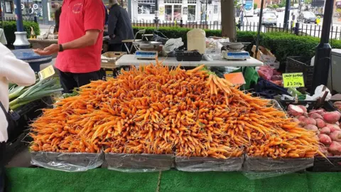 Moseley Farmers' Market Large overflowing boxes of carrots are pictured on a market stall. 