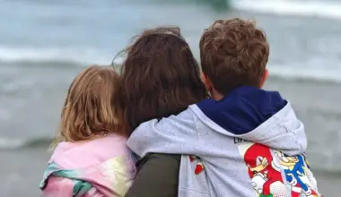 Nikita and her family sit close on the beach, looking at the ocean