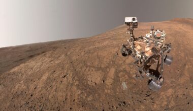 A rover sits on the reddish brownish surface of Mars