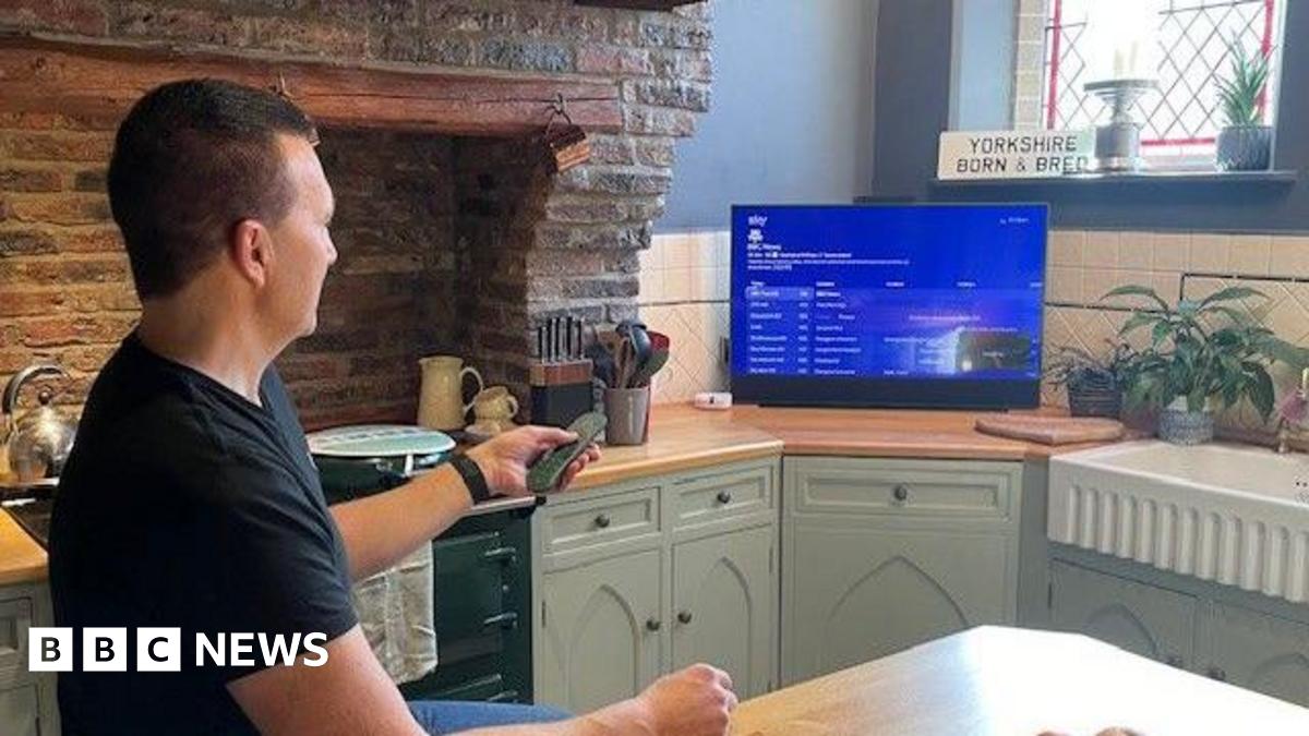 Man with goatee beard in dark shirt in front of a hedge