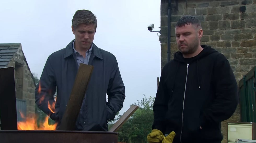 emmerdale, robert and aaron outside watching a burning barrel