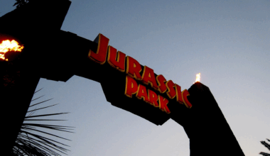 An arch with fiery torches reads "Jurassic Park" in red lettering