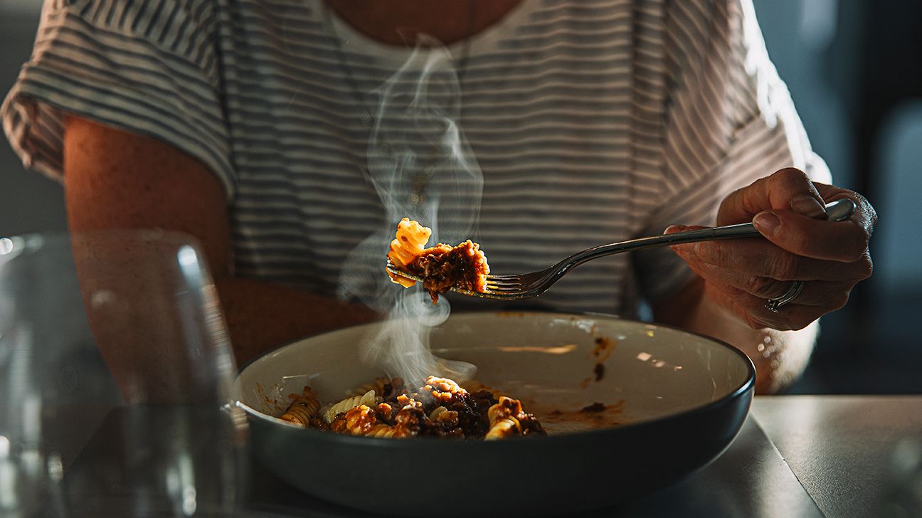 Female eating pasta in the dark