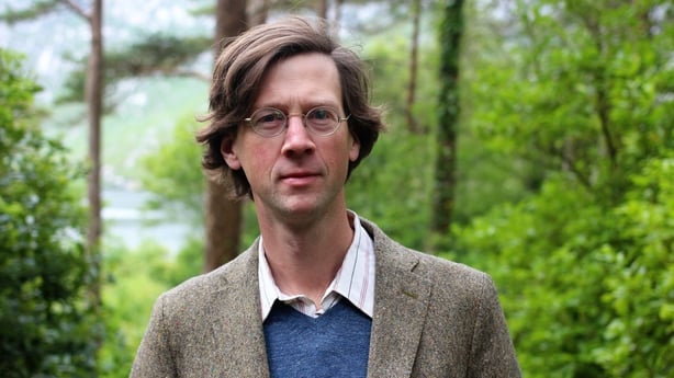 Photo shows writer, broadcaster and documentary maker Manchán Magan against a forest backdrop
