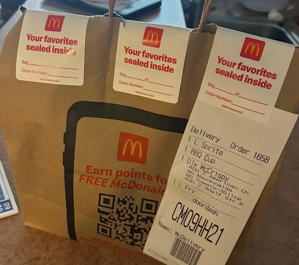 McDonald's delivery order with a sealed paper bag, labeled with order details and a "Your favorites sealed inside" sticker