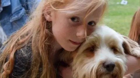 Family handout/PA Wire A picture of Ruth Szymankiewicz, who has long ginger hair, cuddling a terrier dog.