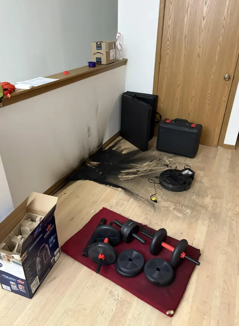 Home gym equipment and a charred wooden floor, showing damage from a small fire