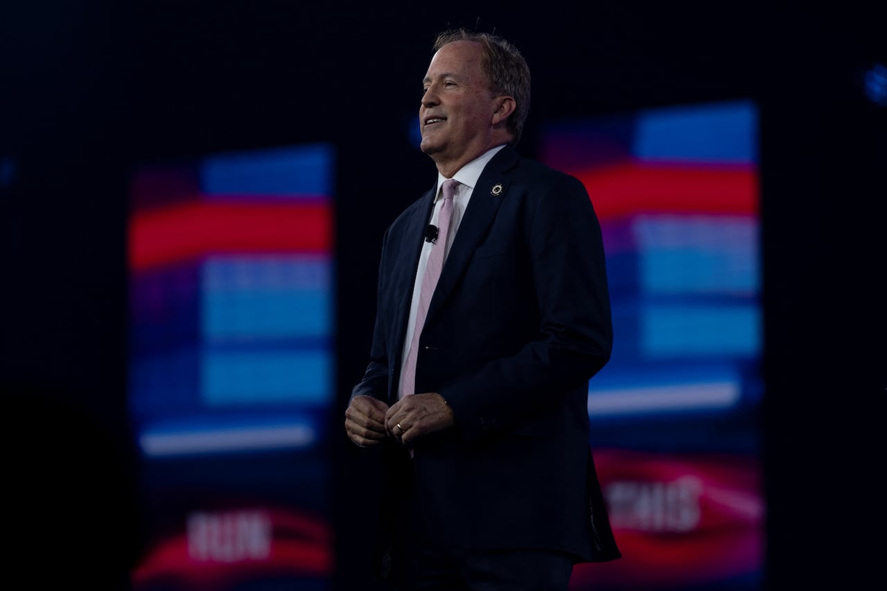 a man in a suit stands on a stage at a political event