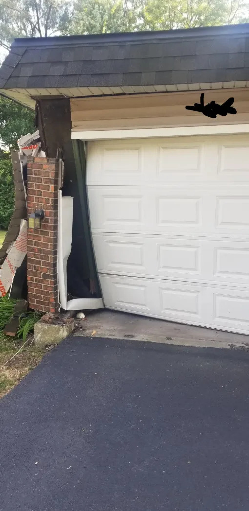 Garage door damaged and partially collapsed with bent frame, revealing some interior