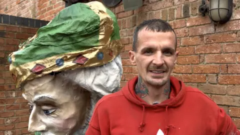 Graffiti artist in red hoodie stood in front of sultan statue